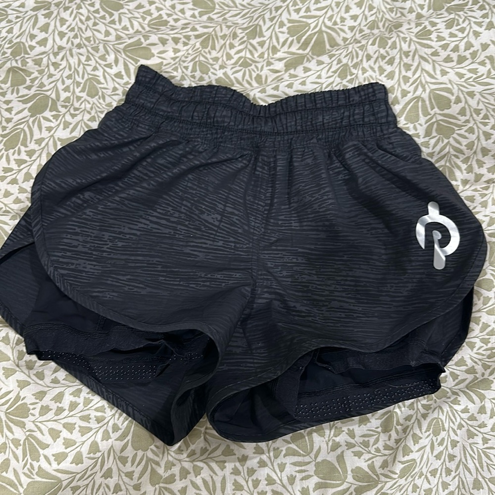 Lululemon shorts with biker shorts underneath with Peloton symbol